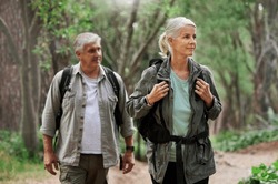 Hiking, looking and senior couple in nature for exercise, holiday walking and enjoying the mountains. Travel, retirement and an elderly man and woman on a walk in the woods or forest for trekking
