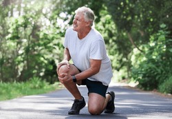 Running, injury and old man with knee pain on path in nature for outdoor fitness and workout exercise. Health, wellness and muscle strain, senior runner with hand on leg in support or relief for ache