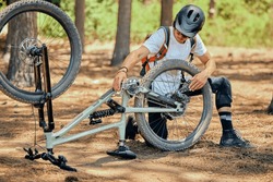 Maintenance, fitness and a man with a bicycle for cycling, fixing a wheel or tire in nature. Training, cardio and a cyclist repairing a bike, doing repairs and inspection for a race or competition