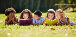 Children, books and lying in park with friends, learning or diversity for reading at school playground. Kids, education or study with support, mockup space or solidarity at multicultural kindergarten
