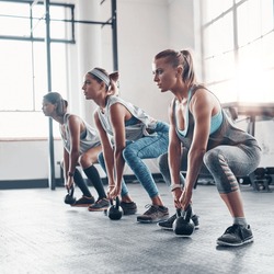 Group, exercise and women training, kettlebell and workout goal with wellness, healthy lifestyle and sports. Female athletes, girls and friends with gym equipment, balance and stretching for cardio