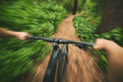 POV, mountain bike and sports person in forest, park and path for adventure, speed and motion blur. Closeup perspective of bicycle handle, fast athlete and cycling action in nature for off road race