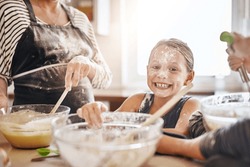 Portrait, playing or messy kid baking in kitchen with a young girl smiling with flour on a dirty face at home. Smile, happy or parent cooking or teaching a fun daughter to bake for child development