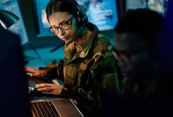 Military control room team, headset and woman with computer and tech for communication. Security, global surveillance info and soldier thinking in army office at government cyber data command center.