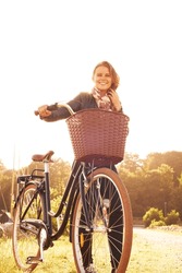 Countryside, nature and portrait of happy woman with bicycle, adventure or travel in morning. Summer, smile and bike with a basket at sunset and person in sunshine with transportation for cycling