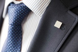 badge on the lapel of his jacket men's shirt with a blue tie