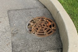 Round storm drain in the street next to a curved curb