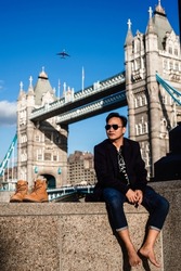 Young adult sitting against tower bridge in London city
