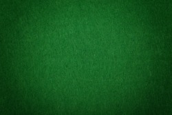 Dark green poker table felt soft rough textile material background texture close up with shade vignette
