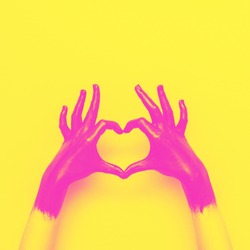 hands in black paint send heart. love and minimal fashion concept. yellow and pink double color effect 