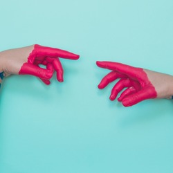 Two painted hands try to reach each other's fingers. Creative connecting conception. 