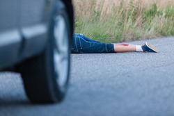 Wounded Legs of a Boy Hit by a Private Car Lying Behind the Vehicle on the Roadway