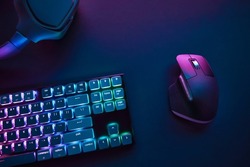 View of pastel neon color backlighted computer keyboard and mouse from above. Professional computer game playing, esport business and online world concept.