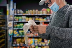 Man in face mask shopping in grocery department store during coronavirus crisis