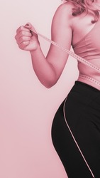 part of Young beautiful girl measuring her slim fit body, monochrome image with pink tint