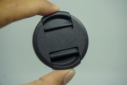 Holding the camera lens cap. Isolated, white background, top view.