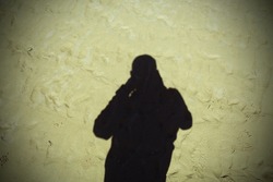 Shadow of the photographer on Crosby Beach in Liverpool Merseyside. The photographer is a young male, the photograph was taken on a warm May afternoon in 2022.