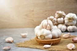 Organic Garlic. Fresh Garlic Cloves and Garlic bulb in wooden basket on dark background with Pile of garlic or spice. Selected focus. Concept of spices for healthy cooking.