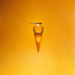 Creative aesthetic summer sunset scene. Ice cream cone with glass sphere and dragonfly on gradient background from gold drop to sunshade orange color.
