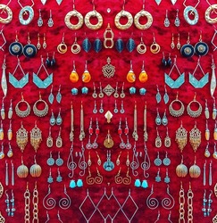 A lot of earrings on a red background. Jewelry on a red velvet background. symmetrical photo