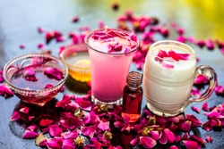 Popular Ramazan drink i.e. Rose falooda or rose shake in a transparent glass along with raw milk in another glass and honey,rose syrup and rose essence also present on the surface with rose petals.