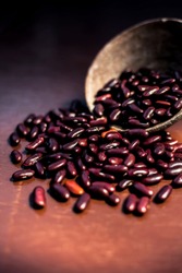 Close up of raw kidney beans on brown colored surface in a clay bowl with a spotlight on it. Vertical shot.