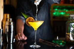 Bartender pouring alcohol on a cocktail in a night club bar