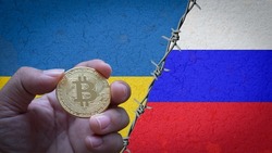 Hand holding a bitcoin gold coin symbol of cryptocurrency on the flag of Russia and Ukraine steps with barbed wire concept illustration of tense two countries diplomatic relations between Russia and U