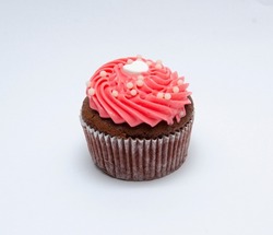 Chocolate cupcake decorated with red pink icing and sprinkles isolated on white
