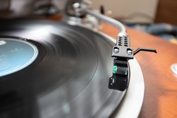 A cartridge and tone arm fitted with a record needle that traces the grooves on an LP record disc.