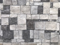 Modern outdoor building stonewall background texture decorated with multicolored split face natural ledge stone tile with regular and rectangular mosaic pattern. Close up
