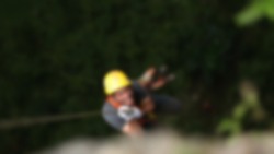 Blurred and defocused abstract background: a man wearing a helmet is looking up and ascending  using a safety rope in a high steep hill. Unrecognizable face.