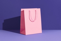 Pink paper shopping bag on purple background. Shopping sale delivery concept. Packaging template mock up