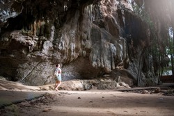 Selective focus, Young woman walking towards a cave. Young woman entering a cave in Krabi, Thailand. Caves in Thailand