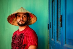 Portrait of tourist in Vietnamese hat. Tourist with Vietnamese conical hat. Bearded man on vacation in Vietnam
