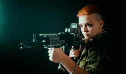 Young woman with red hair, hold machinegun in hands in military uniform