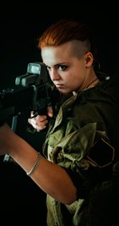 Young woman with red hair, young girl takes aim at the sight in military uniform. Vertical photo