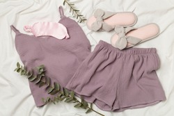 Flat lay composition with beautiful pajamas on white sheet, top view.