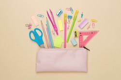 Pink pencil case with school stationery on color backgroung, top view
