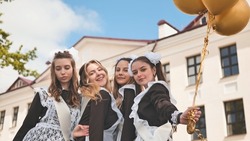 Cheerful Russian girls graduating with orange balloons on the last school day.