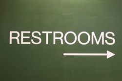 A restroom sign pointing to the right