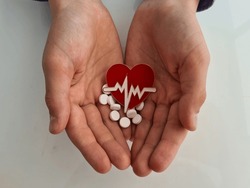 Children hands holds hearts and white pills. Cardiovascular diseases in children and treatment