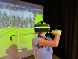 Golfer in virtual glasses plays golf closeup. Golf game indoor simulator