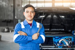 Mechanic Asian man fixing repairing car engine automobile vehicle parts examining screwing using tools wrench equipment working hard in workshop garage support and service in overall work uniform