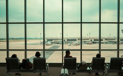 Airport terminal waiting seats for people family silhouette sitting resting waiting for plane to arrive with big window plane view of airport plane parking traffic, travel tourism transport concept