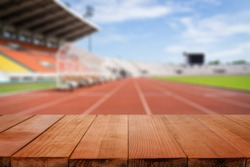 Wood table top on blurred background of Red running tracks in sport stadium  - can be used for display or montage your products