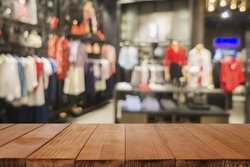 Empty brown wooden table and De focused/blurry background of Sports clothing store with bokeh image luxury and fashionable brand,can be used for montage or display your products