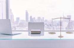 law books,computer and scales of justice on desk in lawyer office and city view.