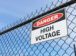 Danger, High Voltage sign on fence with blue sky background