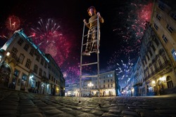 Night street circus performance whit clown balanced in ladder. Festival city background. fireworks and Celebration atmosphere. Wide engle photo